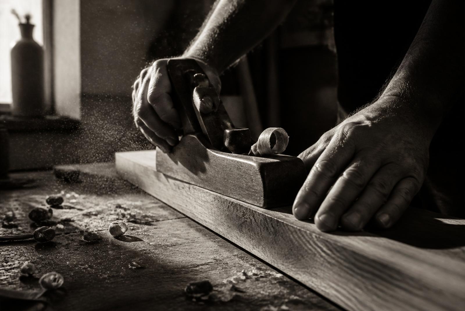 Craftsman hand-planing a walnut board in the Red Kettle atelier
