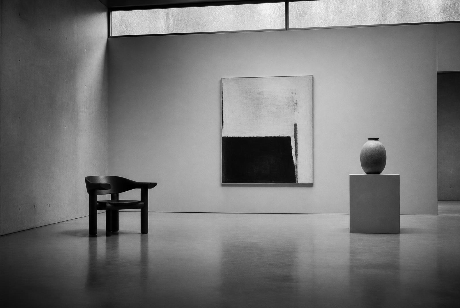 Curated Belgian gallery interior with sculptural chair, painting and ceramic vessel